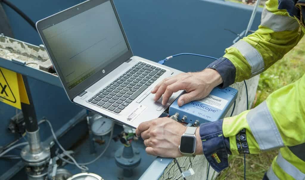 Service engineer with laptop performing potential measuremnts on buried tank